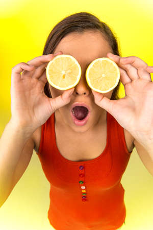 Portrait of beautiful woman holding fresh lemon. girl holding lemons up to eyes and smilingの写真素材