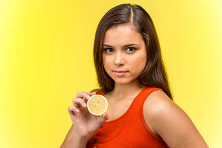 Portrait of beautiful woman holding fresh lemon. profile of girl holding lemon in one handの写真素材