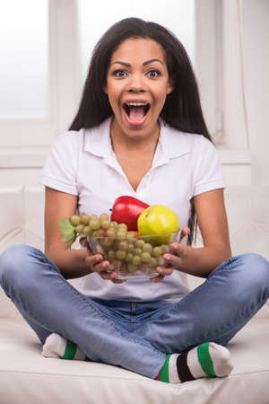 Closeup African AMerican woman with fruits. Beautiful african woman looking into camera and smilingの写真素材