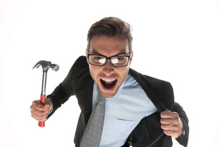 Angry businessman about to hammer on white background. closeup of angry and fierce looking mature guy with hammerの写真素材