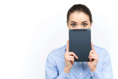 young woman looking out of digital tablet. beautiful girl holding tablet over her face on white backgroundの写真素材