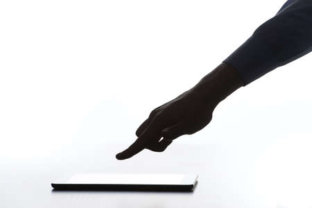 silhouette of hand over modern tablet with blank screen. Touch screen tablet computer with hand on...
