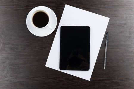 top view of tablet computer with cup of coffee and pen at table. closeup photo of coffee and computer on black tableの写真素材