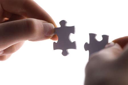 close up of two hands trying to connect puzzle pieces. Hands with two puzzles Isolated on white background の写真素材