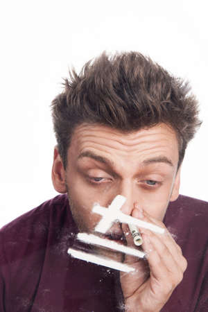 Young man sniffing cocaine from glass. close up of man snorting cocaine linesの写真素材