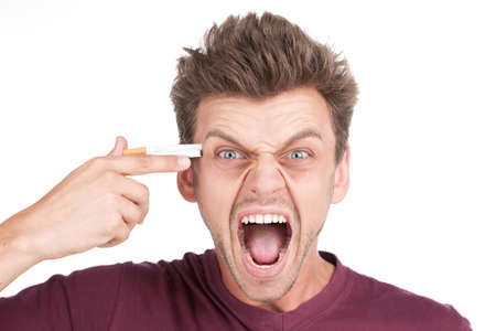 Closeup portrait of frustrated stressed young man. young man placing cigarette on head mimicking gunの写真素材