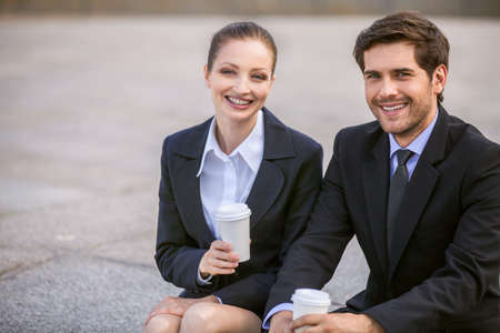 Business people drinking coffee outside. Business partners smiling while on stairsの写真素材