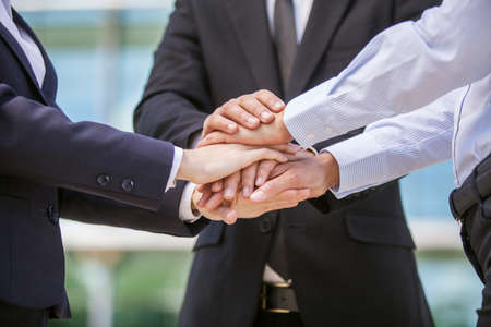 Closeup of business team holding hands together. close-up of three hands on top of each other の写真素材