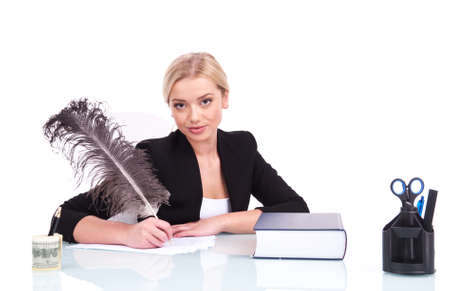 Young businesswoman or teacher working at her desk. beautiful young woman writing at table using featherの写真素材
