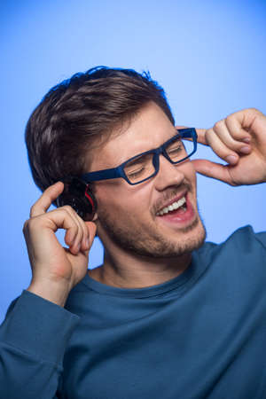 Portrait of young handsome man with headphones. handsome guy standing on blue background の写真素材