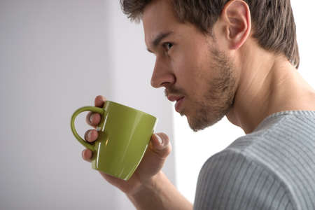 closeup portrait of thoughtful man having coffee. Handsome young man holding mugの写真素材