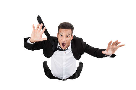 Scared young businessman in falling position. flying businessman on white background and cryingの写真素材