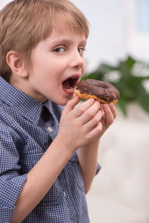 cute caicasian boy open mouth. nice little boy eating sweet donut の写真素材