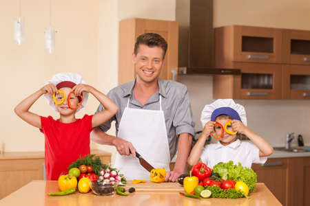 Young family preparing salad together. boy and girl playing with food at kitchenの写真素材