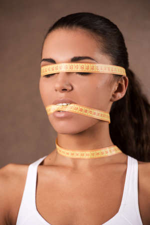 Young woman with meter that shuts her mouth. portrait of beautiful girl with meter covering her faceの写真素材