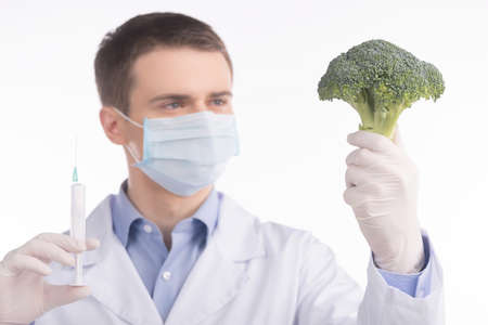 green broccoli in genetic engineering laboratory. man holding broccoli and needle on white backgroundの写真素材