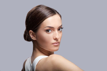 Young beautiful female model in white dress. Beautiful luxury woman model posing with open back の写真素材