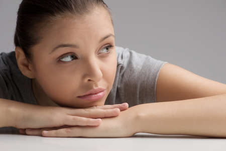 Portrait of beautiful young woman leaning on hands. pretty eyes of girl isolated on grey backgroundの写真素材
