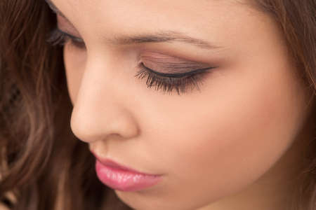Portrait of attractive girl with make-up looking down. Beauty portrait of young woman looking downの写真素材
