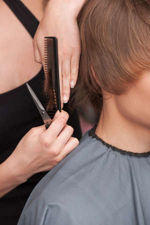 closeup on hands of hairdresser cutting hair of man client. closeup on man head sitting in hair salonの写真素材