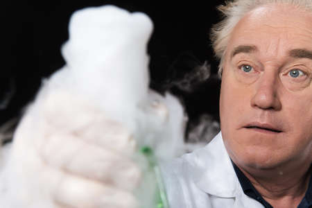 surprised clinician studies in laboratory and holding flask. closeup on man sitting on black...