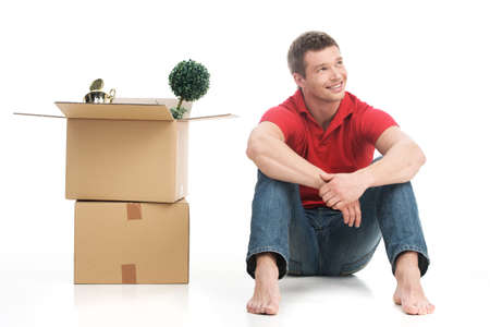 Smiling young man with cardboard box and looking up. Happy young man moving into new houseの写真素材
