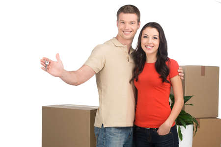 couple celebrating new home with keys and moving boxes. Happy couple moving into new apartment.