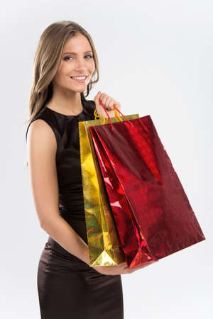 Shopping woman holding bags isolated on white background. Side view of girl with colorful bags looking into cameraの写真素材