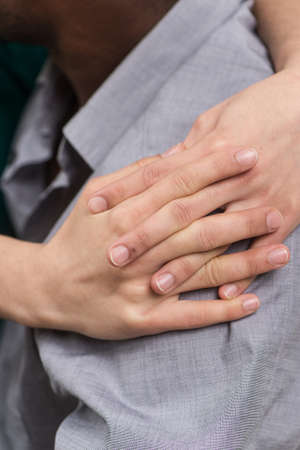 closeup of girl hands hugging boyfriend shoulder. side view of black man wearing shirtの写真素材