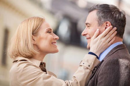 Portrait of amorous couple touching faces and laughing. blond woman looking at man and smilingの写真素材