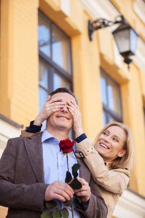 girl covering her boyfriend's eyes to surprised him. Couple in love - woman cover eyes of man having funの写真素材