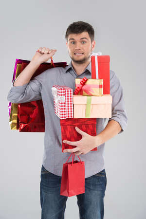 young guy holding stack of boxes. surprised male making scared face on grey backgroundの写真素材