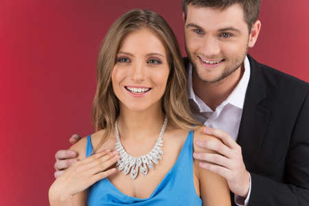 Closeup on man looking at necklace on girl's neck. man standing behind woman wearing jewelryの写真素材