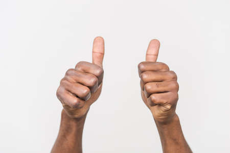 Man congratulates winner and holding his thumbs up. Closeup of male hand showing thumbs up sign against white backgroundの写真素材