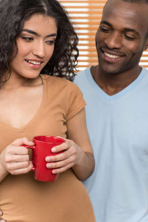 pretty woman holding cup and man looking at her. African man and Hispanic woman standing close before shuttersの写真素材