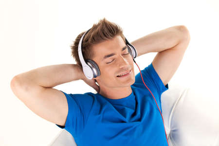 Happy man in headphones relaxing on sofa at home. handsome guy top view resting while closed eyesの写真素材