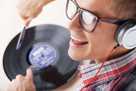 Young man working as dj with ear-phones and disc. closeup photo of man face holding fork and knife