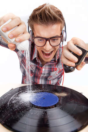 Young man working as dj with ear-phones and glasses. closeup photo of mad man pouring salt and paper on diskの写真素材