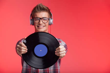 portrait of young man holding disk and wearing headphones. の写真素材
