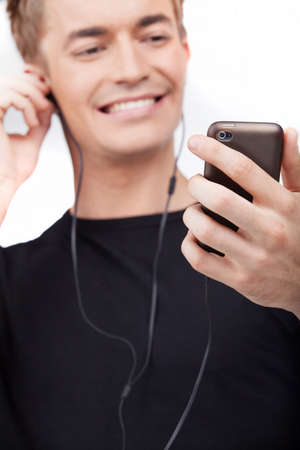 Portrait of young man listening music on cell phone.の写真素材