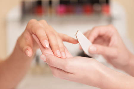 Woman in nail salon receiving manicure. manicurist holds hands of client in beauty salonの写真素材