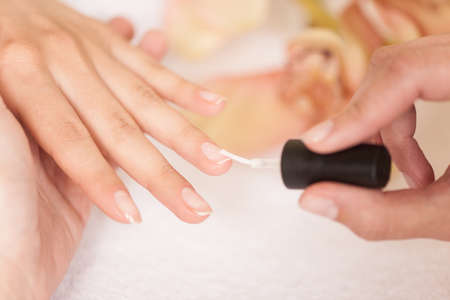Woman in nail salon receiving manicure by beautician. closeup of female hand resting on white towel