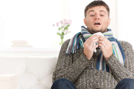Man blowing his nose in his living room.の写真素材
