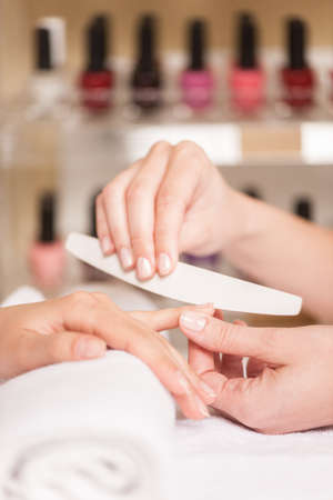 Close-up of beautician hand filing nails of woman in salon. manucurist women sitting in spa salon and relaxingの写真素材