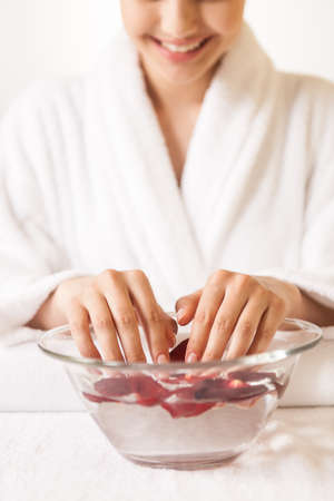 Woman hands in glass bowl with water on white towel. front view of girl holding her beautiful hands in water and smilingの写真素材