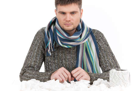 Man having cold with tissue on table and box of tissues. exhausted allergic man sitting at tableの写真素材