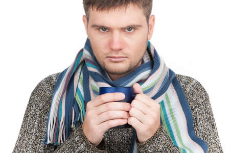 Portrait of sick man holding cup of tea. man wearing scarf and looking at cameraの写真素材