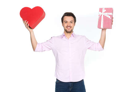 Man holding presents wrapped in gift paper, isolated on white. waist up of guy holding heart shaped boxes and smilingの写真素材