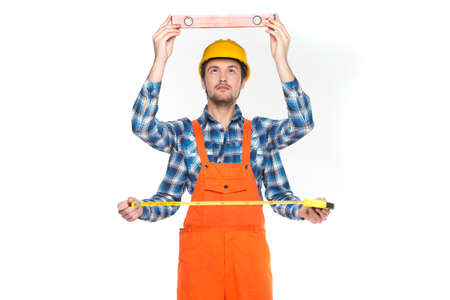 Construction worker measuring over white background. man full portrait holding meter and having four armsの写真素材