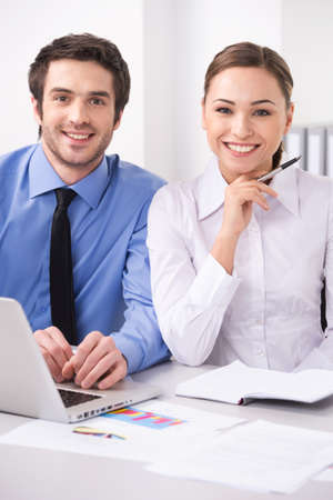 Beautiful successful young businesswoman with friendly smile. Two colleagues in office in front of computerの写真素材